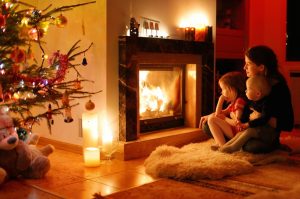 Young mother and her daughters by a fireplace on Christmas