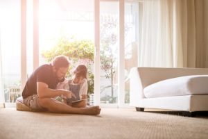 Father and daughter looking at digital tablet by open sliding door